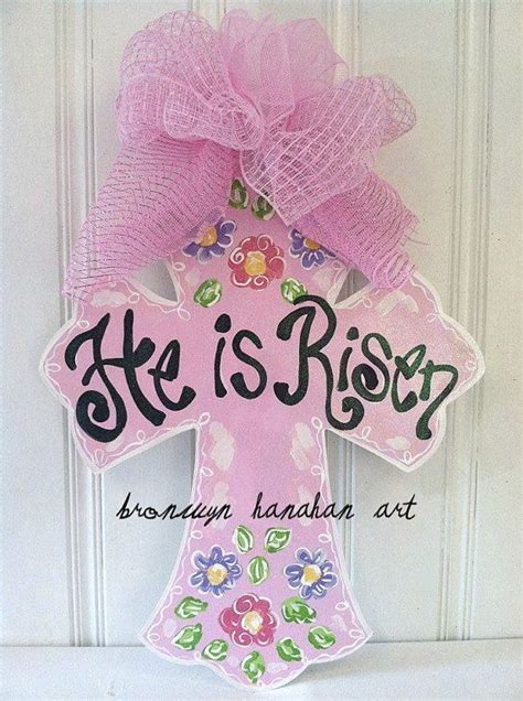 A Pink Door Hanger With The Words He Is Risen On It