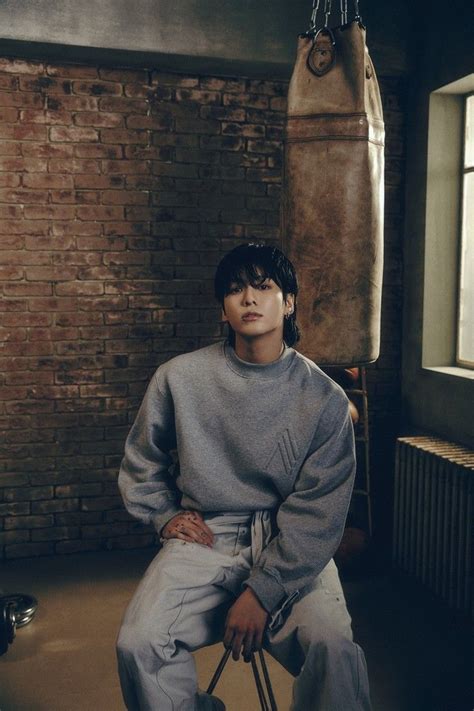 A Young Man Sitting On Top Of A Suitcase In Front Of A Brick Wall With