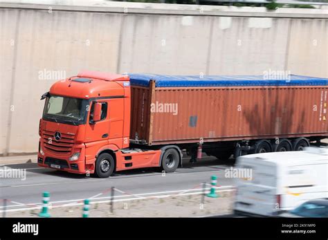 Red Mercedes Actros Truck Loading A Red Container Trailer Along The