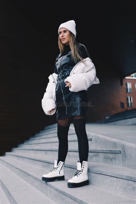 Long Haired Blonde Wearing A White Woollen Cap A White Jacket With A Curvaceous Black Leather