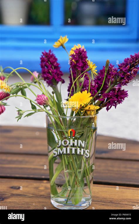 Handful of wild flowers, orchids and dandelions, in a John Smith's beer ...