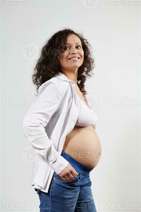 Sexy Curly Haired Pregnant Woman In Sixth Month Of Pregnancy Smiling Posing With Bare Belly