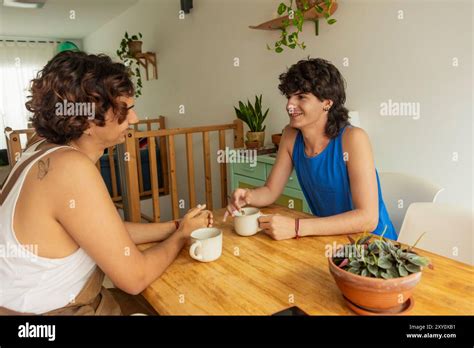 A Gay Couple Shares A Pleasant Moment Over Morning Coffee In Their Cozy Dining Area Reflecting