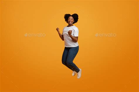 Excited Young African American Lady Jumping In The Air Stock Photo By