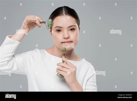 Mujer joven con síndrome de Down usando rodillos de jade aislados en