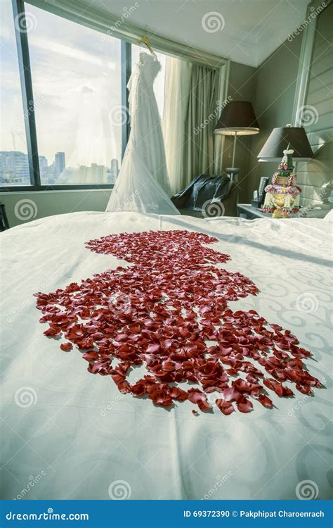 Wedding Dress And Groom Suit In Room With Rose Petals On A Bed Stock