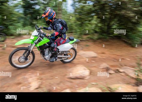 Woman on off road bike racing up a hill on a rough trail Stock Photo ...