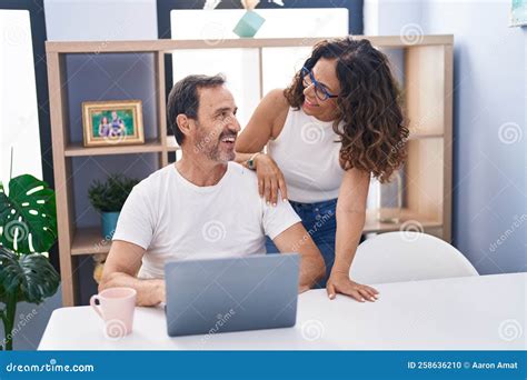 Pareja De Hombres Y Mujeres Sonriendo Confiados Usando Laptop En Casa