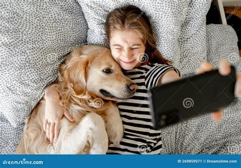 Chica Con Perro Recuperador De Oro En La Cama Imagen De Archivo