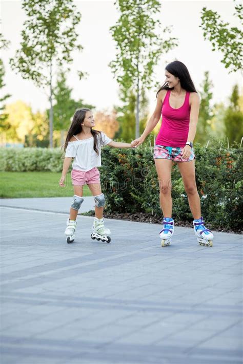 Joven Madre Y Su Pequeña Hija Patinando En Patines Imagen de archivo