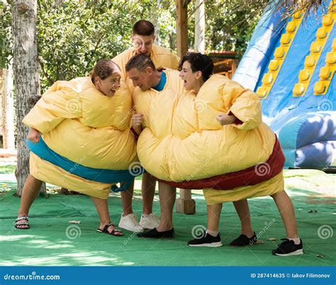 Men And Women In Sumo Suits Fighting In Outdoor Amusement Park Stock