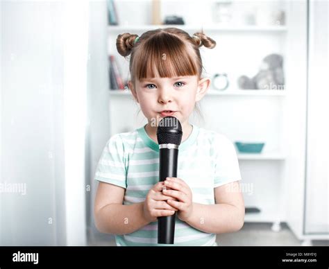 Cute little girl singing karaoke at home Stock Photo - Alamy