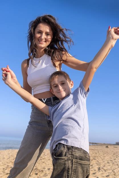 Feliz madre e hijo jugando en la playa en un día soleado en sundet