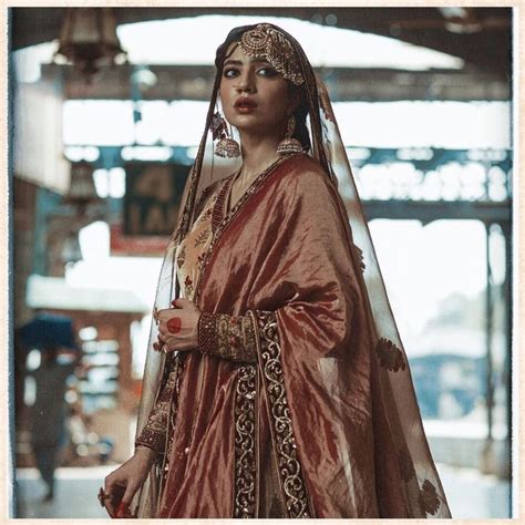 a woman in a bridal gown and veil standing on the street with her hand ...