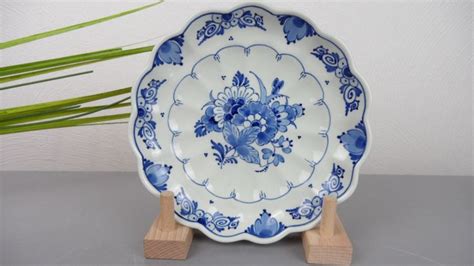 A Blue And White Plate Sitting On Top Of A Wooden Stand Next To A Plant