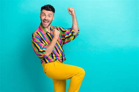 Photo Of Positive Satisfied Impressed Man With Brunet Hair Dressed Striped Shirt Raise Fists Up