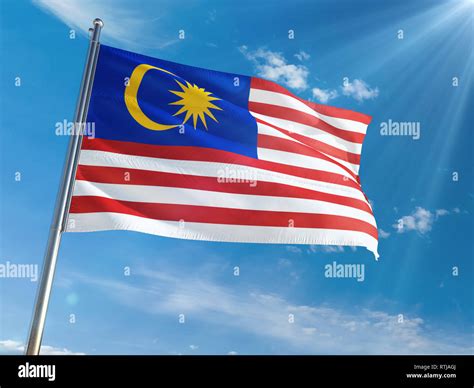 Malaysia National Flag Waving On Pole Against Sunny Blue Sky Background