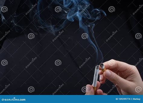 La Main Tient La Cigarette De Tabagisme Sur Le Fond Noir Photo Stock