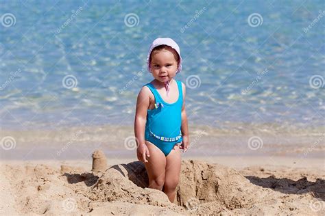 Child Girl Is Playing On Sandy Beach Near Blue Sea Stock Photo Image