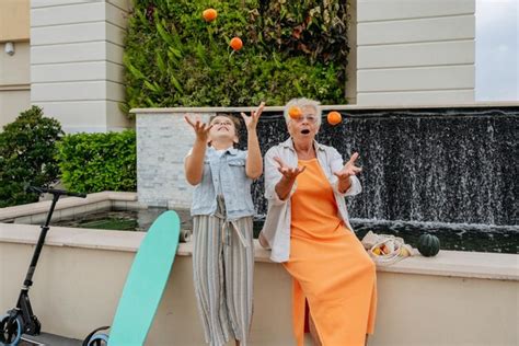 Premium Photo Happy Grandmother And Granddaughter Playing With Mandarins