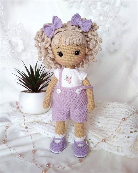 A Crocheted Doll Sitting Next To A Potted Plant On A White Blanket