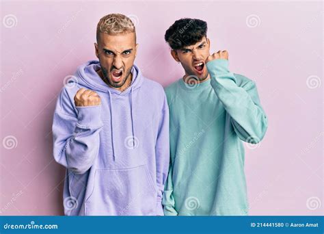 Homosexual Gay Couple Standing Together Wearing Casual Clothes Angry And Mad Raising Fist
