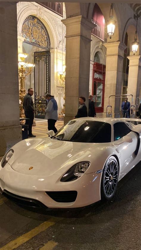 A White Sports Car Parked On The Street In Front Of A Building With