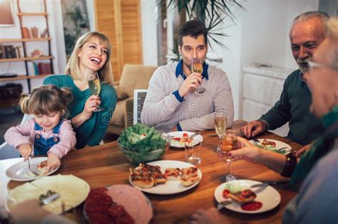 Familia Que Disfruta De La Comida Alrededor De La Tabla En Casa Foto De