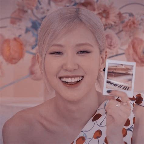 A Woman Holding Up A Card And Smiling At The Camera With Flowers In The