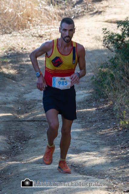 A Man Running Down A Dirt Road With Trees In The Background