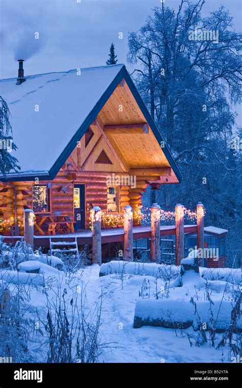 Log Cabin In The Woods Decorated With Christmas Lights At Twilight Near