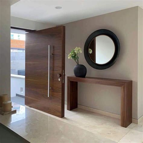 A Modern Entry Way With A Mirror And Vase On The Table Next To It