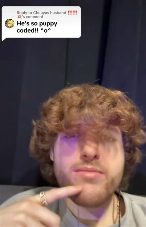 A Man With Curly Hair Is Looking At The Camera And Has His Finger On