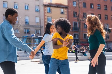 Jovens amigos multiétnicos dançando e sorrindo um grupo quadrado da