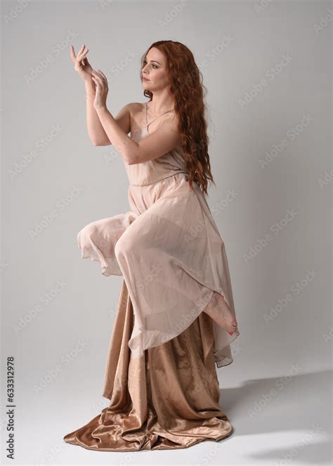 Full Length Portrait Of Beautiful Female Model With Long Brunette Hair Wearing A Creamy Pink