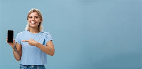 Une Jolie Fille énergique Montrant Un Smartphone Une Jeune Femme Blonde Charmante Avec Des