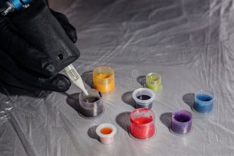 Tattoo Artist Dipping Machine Needle Into Ink At Table Stock Photo