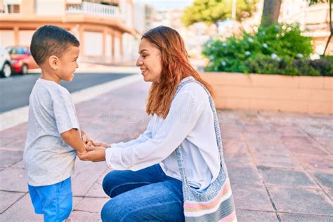 Adorable Madre Latina E Hijo Sentados En El Banco Y Leyendo Un Libro En El Parque Imagen De