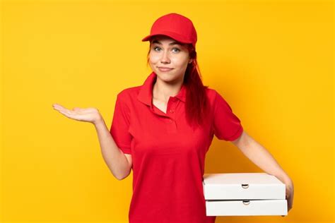 Premium Photo Pizza Delivery Girl Holding A Pizza Over Isolated Background Having Doubts While