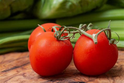 Organic Red Tomatoes On The Vine Arranged On Olive Wood Solanum