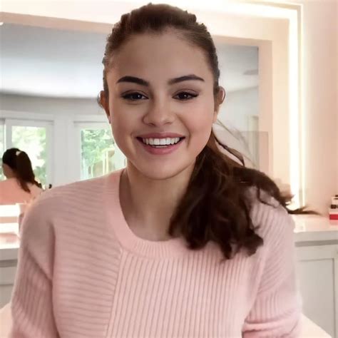 A Woman In A Pink Sweater Is Smiling At The Camera And She Has Her Hair