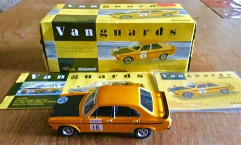 An Orange Toy Car Sitting On Top Of A Wooden Table Next To Two Boxed Books