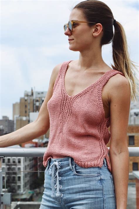 A Woman Standing On Top Of A Roof With Her Hand In Her Pocket And Looking Off Into The Distance