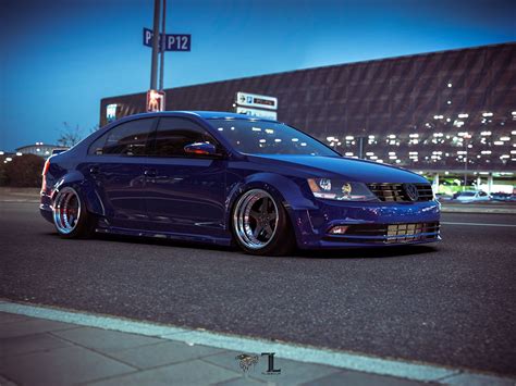 A Blue Car Is Parked On The Side Of The Road In Front Of A Building