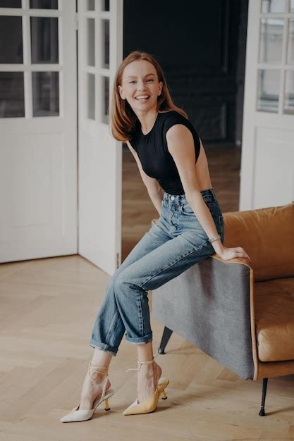 Niña sonriente con ropa informal sentada en un acogedor sofá posando