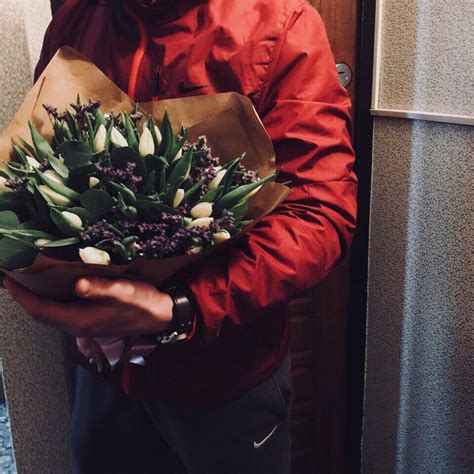 A Man Holding A Bouquet Of Flowers In His Hands