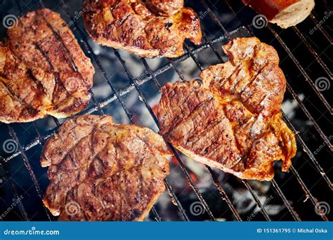 Juicy Beef Steaks On Grill With Flame On Barbecue In The Garden Stock