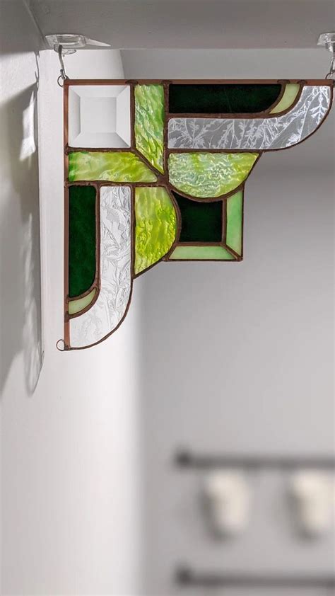 A Green And White Stained Glass Window Hanging From The Ceiling In A