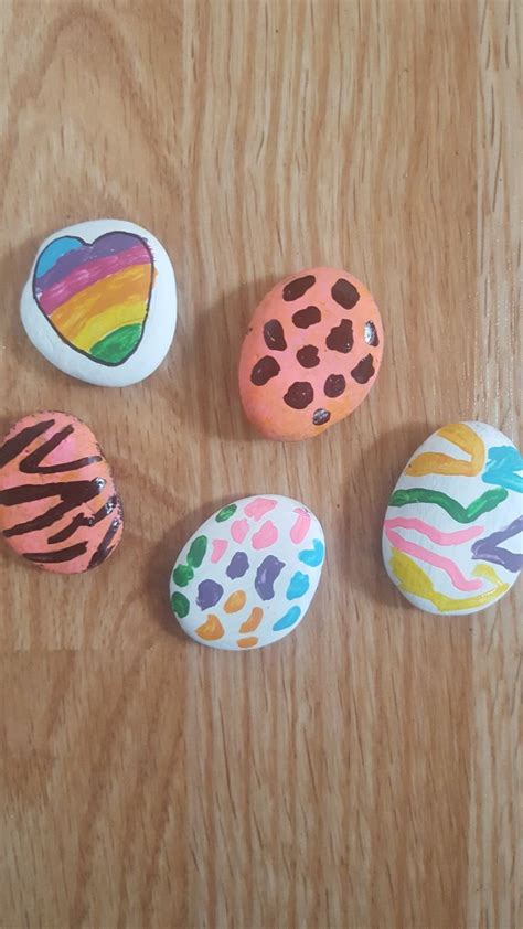 Four Painted Rocks Sitting On Top Of A Wooden Table