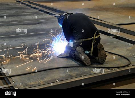 Proceso De Soldadura Un Soldador De Rodillas Suelda Estructuras